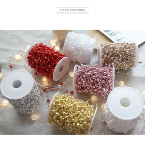 Detail of multi-color Christmas bead chains on spools for festive DIY decorations