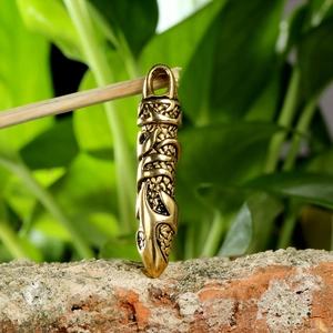 Close-up of bronze dagger pendant with Celtic dragon scales texture on a rustic background