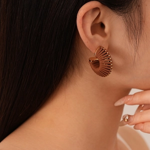 Detail of vintage C-shaped brown leather earrings with gold metallic stripes on model