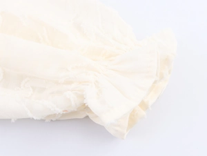 Detailed close-up of cream white ruffled elastic cuffs with textured jacquard fabric