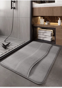 Gray memory foam bath mat with wave pattern on modern bathroom tile floor