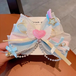 Detail of a large gradient lace bow hair clip with heart wings and pearl chain
