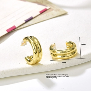 Macro detail of golden double-layer C-shaped earrings with 18k plating on a stone surface