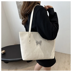 Chic off-white tote bag featuring a silver bow detail and dual shoulder straps