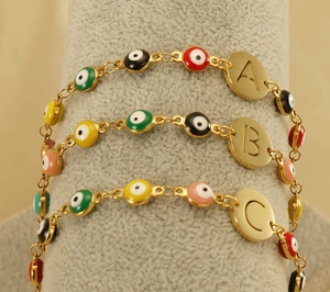 Detailed close-up of golden evil eye bracelets with personalized alphabet letter charms