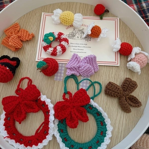 Close-up of handmade crochet Christmas ornaments like wreaths and apples on a wooden tray