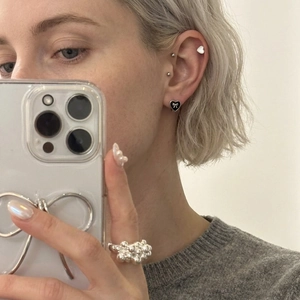 Minimalist black heart hoop earrings and textured silver ring set on a model
