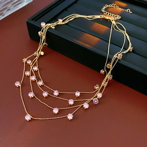 Détail du collier doré multi-rangs avec pierres roses sur un support d'exposition