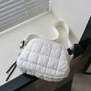Detail showing white quilted puffer crossbody bag with adjustable strap and black zipper pull