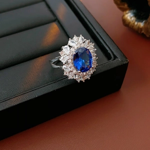 Vista macro di un anello da cocktail in argento con gemma blu ovale e piccoli diamanti