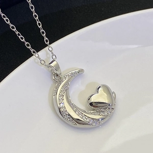 Macro shot of silver crescent moon and heart pendant necklace with shimmering zircon stones