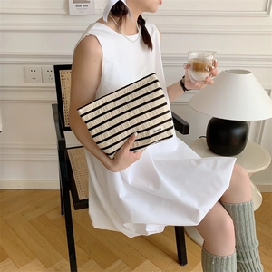 Detail of a large knitted striped makeup bag held by a model in a cozy lifestyle setting