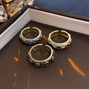 Detail of three vintage gold adjustable rings with red green and blue gemstones in a box