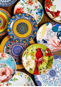 Artistic stack of 9-inch ceramic plates with floral and bird patterns on wooden surface