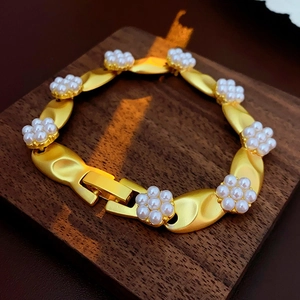 Detail of vintage gold pearl bracelet with floral motif on a dark wooden tray