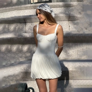Détail d'une robe bustier blanche à bretelles avec jupe courte plissée sur des marches