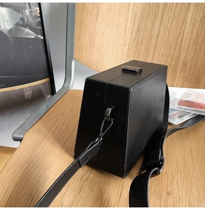 Detail of black box crossbody bag showing premium leather texture and metallic lock