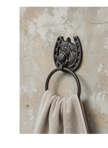 Detail of vintage cast iron horseshoe towel ring with embossed horse head on rustic wall