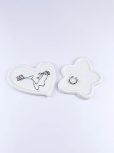 Close-up of white heart and flower-shaped jewelry trays with black speckled texture