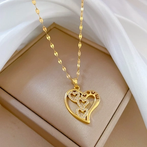 Golden heart necklace with LOVE engraving and crystal charms in a beige jewelry box