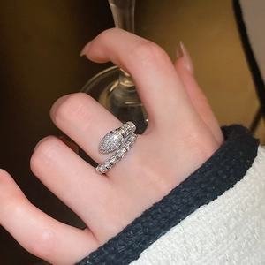 Detail of silver snake ring with cubic zirconia pave on a hand holding a glass
