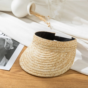 Detail of hand-woven straw visor with black elastic sweatband on a wooden surface