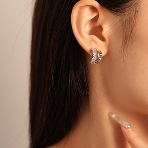 Detail of silver C-shaped double hoop earring with cubic zirconia and studded texture