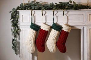 Detail of four cable knit Christmas stockings hanging on a white festive fireplace
