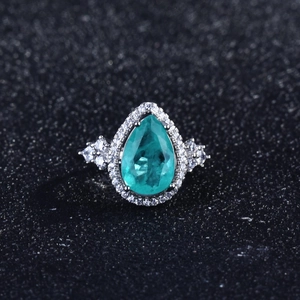 Close-up of luxury water-drop green gemstone ring with pavé diamonds in silver setting