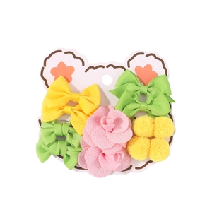 Children's hair accessory set with colorful bows and floral pompoms on a bear card