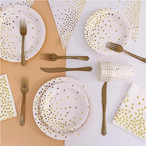 Flat lay of white paper plates and cups with gold foil dots for party decorations