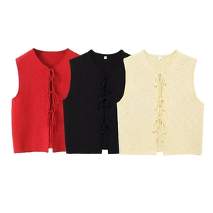 Three V-neck knitted vests with bow ties in red, black and beige on white background