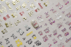 Detailed view of cherry and bow nail art stickers with metallic gold glitter finish