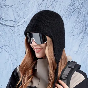Women's black knit wool beanie with ear flaps and ties shown in outdoor winter scenery