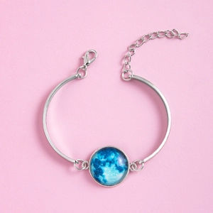 Detail of silver bangle featuring a blue moon pendant with adjustable lobster clasp chain