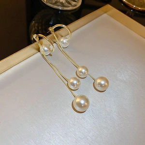 Détail de boucles d'oreilles longues en chaîne dorée avec perles sur un plateau