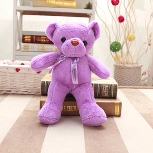 Primer plano de un suave oso de peluche lavanda púrpura sentado sobre libros decorativos