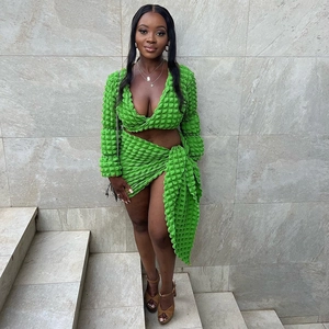 Detail of bright green bubble textured fabric on two-piece cropped top and slit skirt set