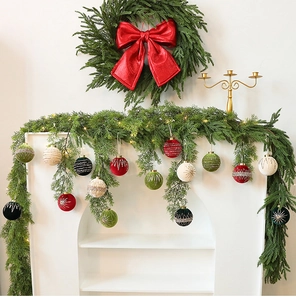 Detailed view of flocked Christmas balls in festive colors hanging on fireplace garland