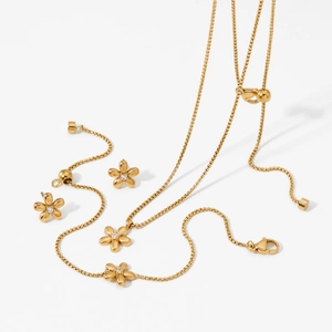 Golden flower necklace and earrings set with small crystals on a white background