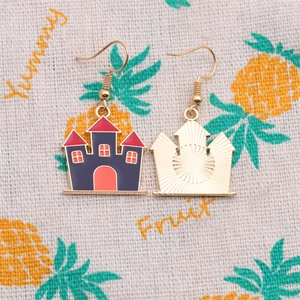 Détail de boucles d'oreilles château d'Halloween dorées avec émail bleu et crochet
