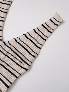 Détail d'une robe en maille rayée crème et noir montrant la texture côtelée du tissu