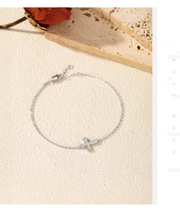 Macro shot of silver cross pendant bracelet with sparkling stones on textured background