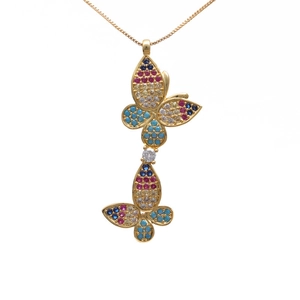 Macro detail of gold butterfly pendant with colorful zircon stones on white background