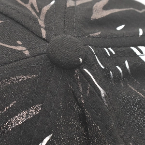 Macro shot of baseball cap top button with silver abstract print on black fabric