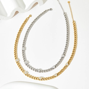 Gold and silver Cuban chain necklaces with heart cubic zirconia charms on white background
