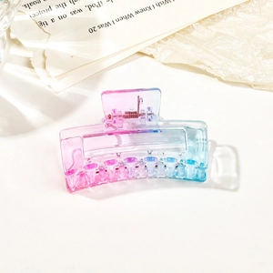 Close-up of a gradient pink to blue transparent square hair claw clip on paper