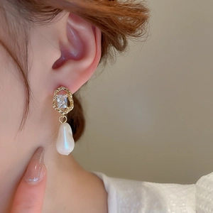 Close-up of model wearing baroque pearl earrings with gold frames and zircon stones