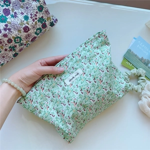 Close-up of small floral cotton toiletry bag with simple wish label in hand