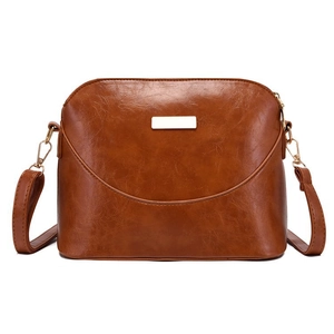 Detail of vintage textured leather on brown shell bag with elegant gold metal buckle hardware